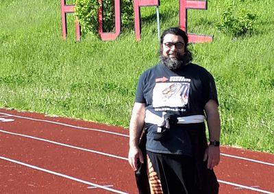 Majdi poses for camera while standing on a red race track and a sing behind him spells "hope"