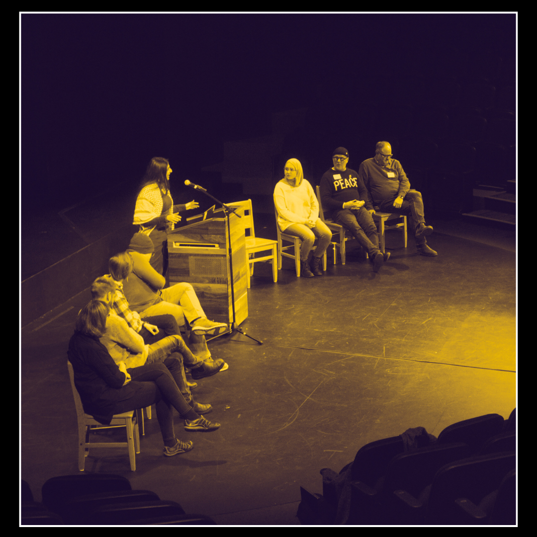 Woman speaking at podium surrounded on the sides by other panelists sitting down.