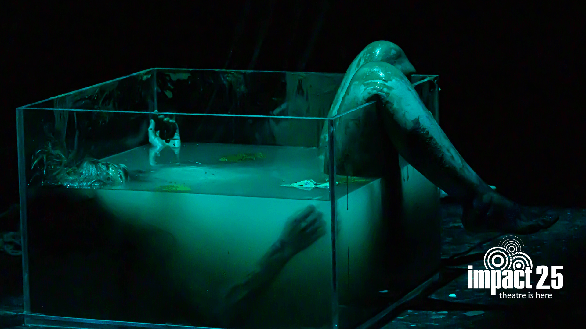 A person laying in a glass box filled with blue liquid